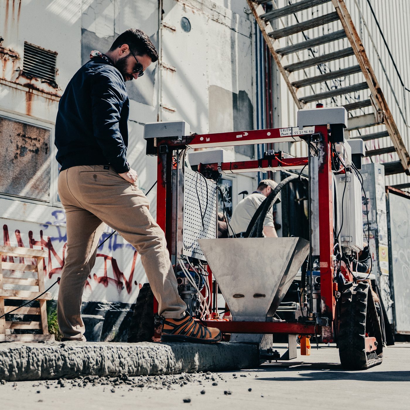 An ERLEtek co-founder positions the mobile printer robot before a demo wall pour.