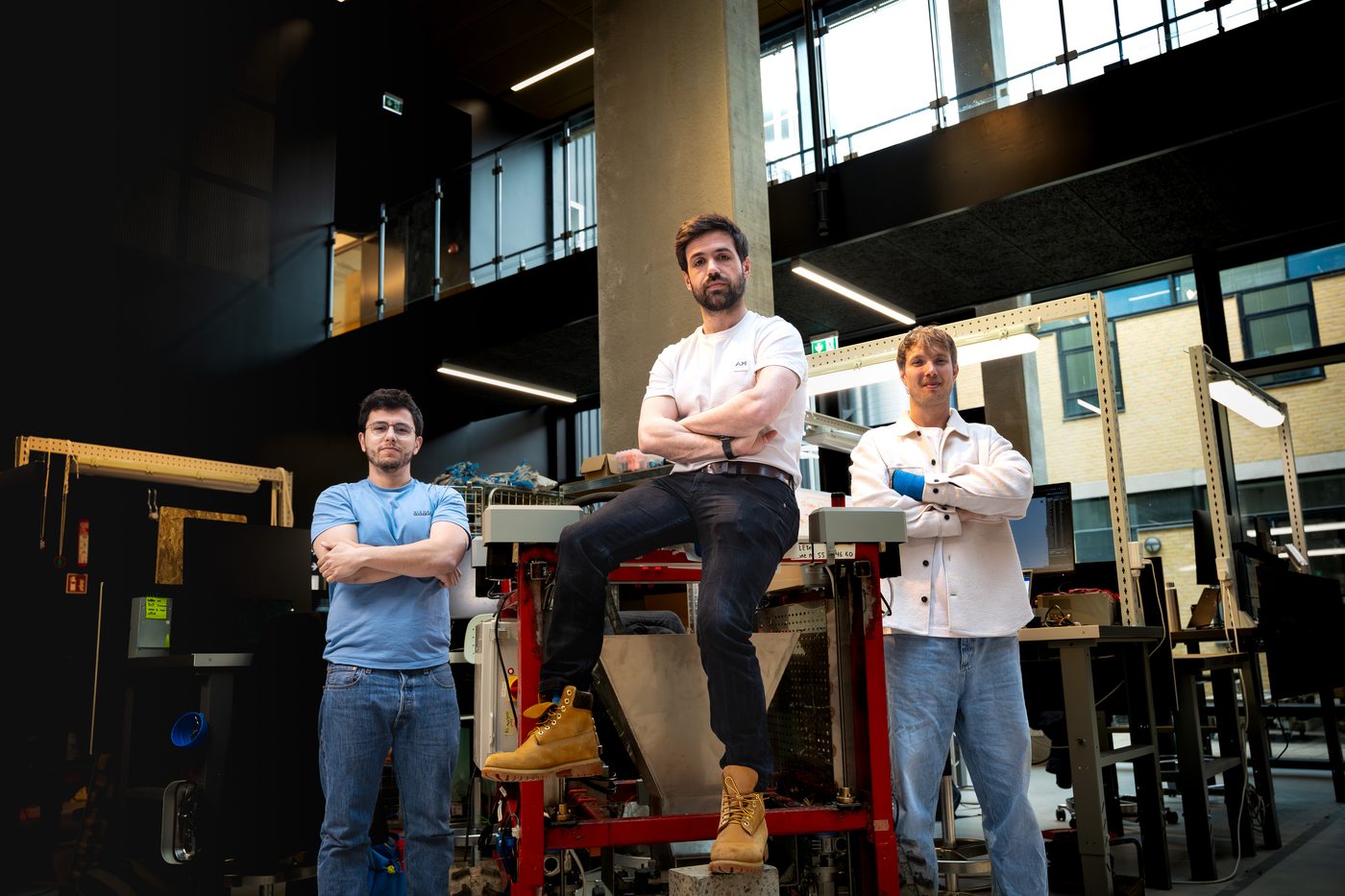 ERLEtek's three co-founders at DTU Skylab, standing and seated around the printer robot.